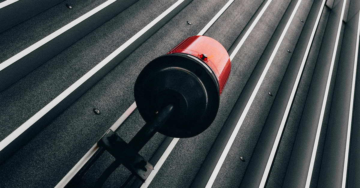 Red alarm light against a metal wall with vertical ridges