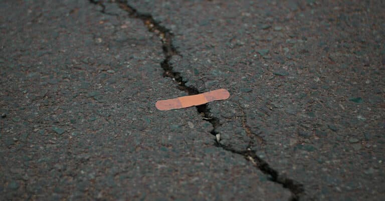 Large crack across concrete with small ineffective bandaid placed on it